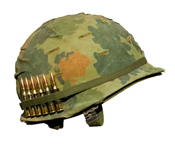 A US military helmet with an M1 Mitchell pattern camouflage cover from the Vietnam war, and six rounds of 7.62mm ammunition.