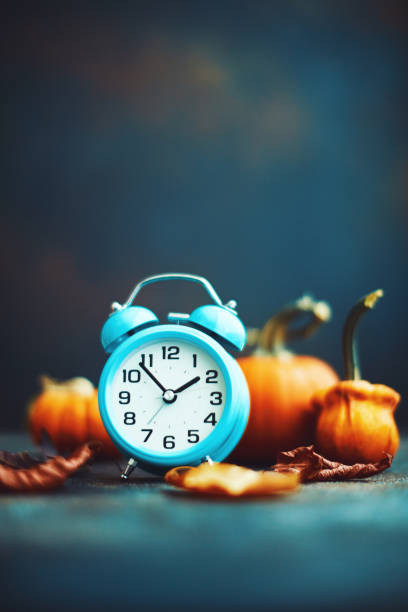 istock Time for Fall. Alarm clock with leaves and pumpkins. Daylight Savings Time. 1184498996