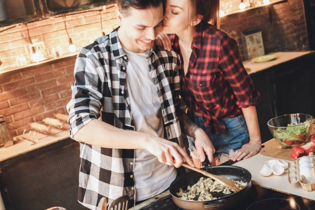 Happiness husband making dinner when perfect wife kissed him stock photo