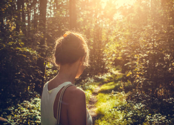 istock Woman walking alone in the forest 1184502681