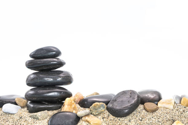 istock Stack of black basalt balancing stones on sand, on white background. 1184502775