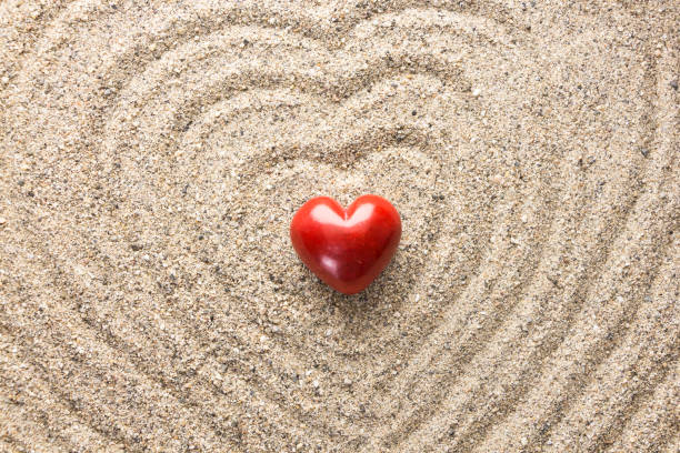 istock Red heart shaped stone on sand surface forming heart waves 1184502789