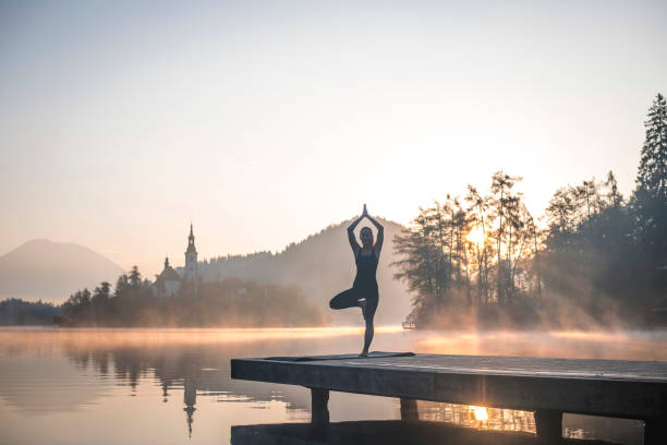 istock Young Woman in Yoga Tree Pose on Pier Overlooking Lake Bled 1184503070