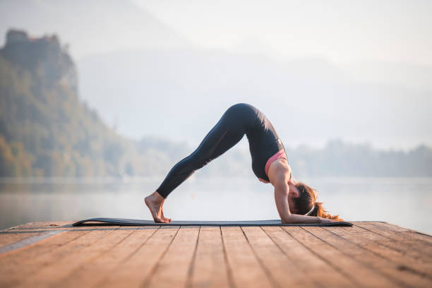 istock Young Woman in Dolphin Pose on Pier Overlooking Lake Bled 1184503079
