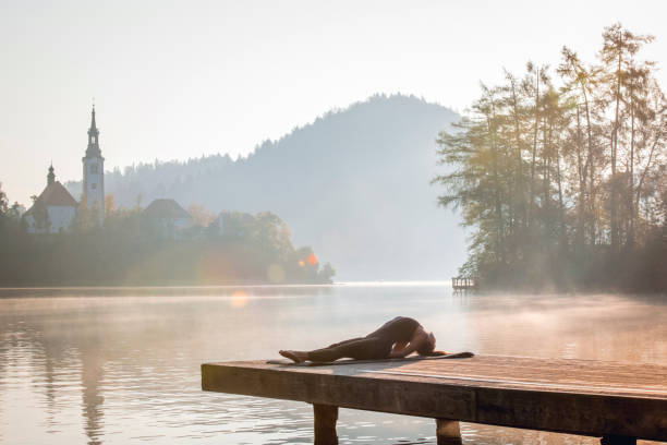 istock Yoga Fish Posture on Lake Bled Pier with Lens Flare 1184503080