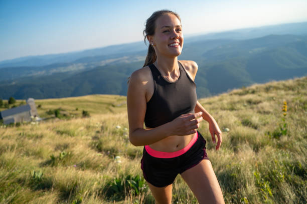 Smiling Young Woman Jogging on Top of a Hill stock photo