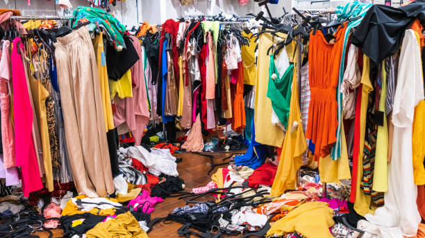 colorful garments on racks and on the floor; fast fashion concept - monte roupa imagens e fotografias de stock