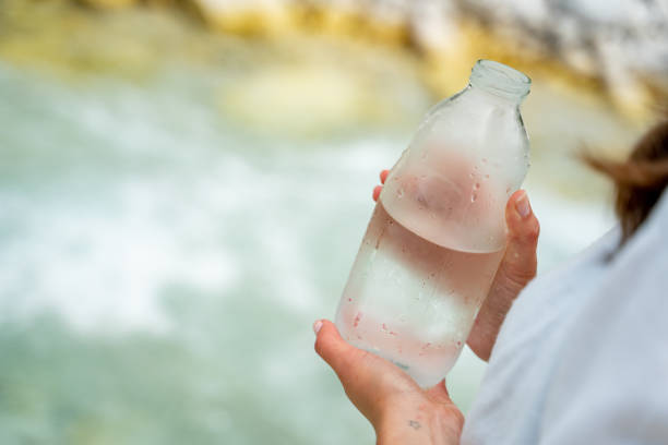 mujer joven sosteniendo botella recién llena con agua fría - number of people riverbank river flowing water fotografías e imágenes de stock