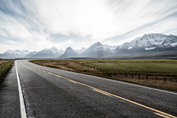 Strada di campagna verso montagne innevate contro il cielo, Canada - foto stock