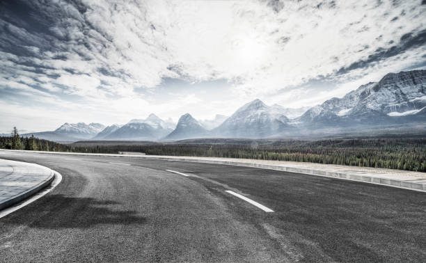 istock Empty road travel through lush forests and snow-capped mountains 1184512428