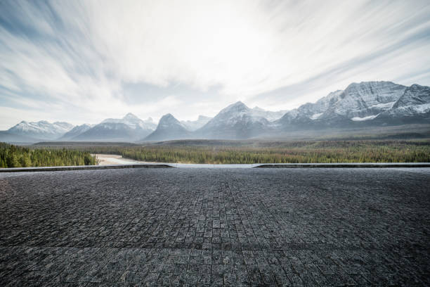 carretera asfaltada vacía con un paisaje dramático sobre el fondo - rocky mountains canada mountain winter fotografías e imágenes de stock