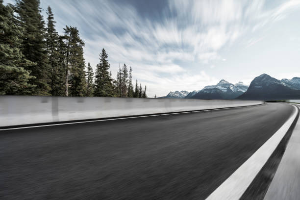 istock Empty road travel through lush forests and snow-capped mountains 1184513042