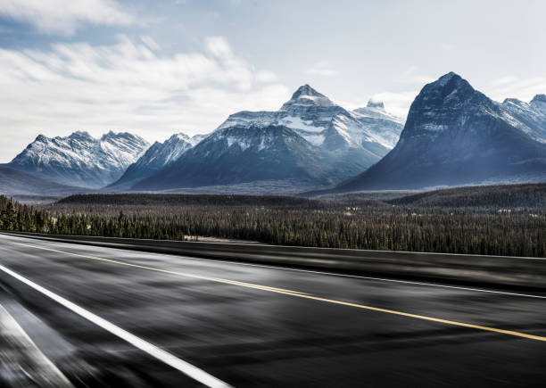istock Empty road travel through lush forests and snow-capped mountains 1184513098