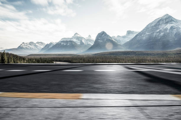 istock Empty road with lush forests and snow-capped mountains in background 1184513129
