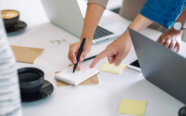 istock businessman discussing, writing and pointing finger at notebook on the table in office 1184515524