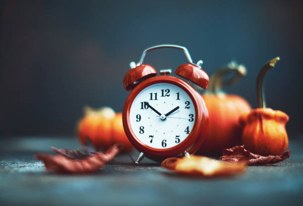 istock Time for Fall. Red alarm clock with leaves and pumpkins 1184527849