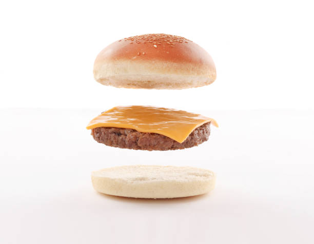float,fly burger layers with steaks and cheddar on white background