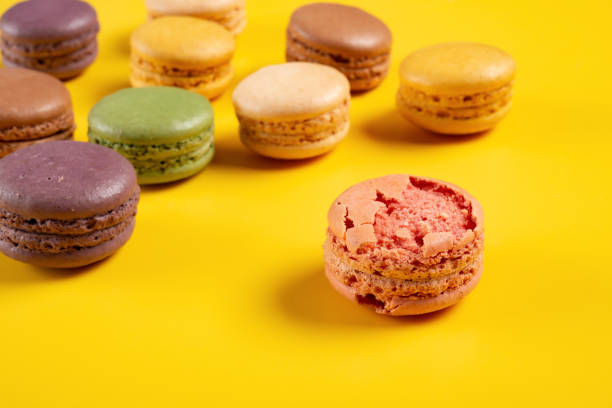 istock broken pink macaroon on yellow background with  different colors macaroon on back 1184534671