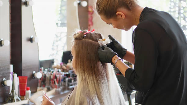 A hairdresser is installing the upgrade of hair extension. stock photo