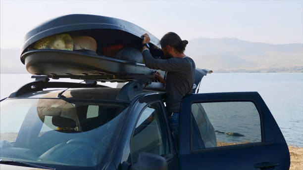 Young bearded man taking out a camping equipment from car roof box stock photo