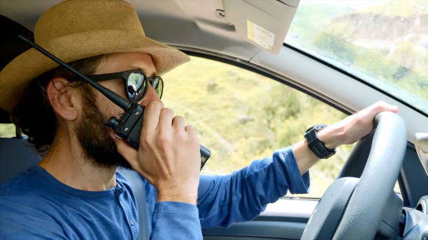 Man is talking on walkie talkie during driving off-road car in mountain valley. stock photo
