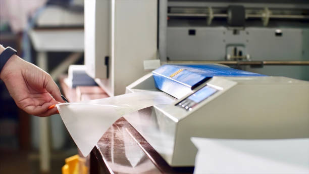 Woman is laminating paper in laminating machine laminator in typography. stock photo