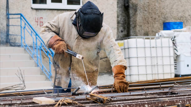 istock Welder at construction site is welding pipe with electrode in helmet. 1184545824