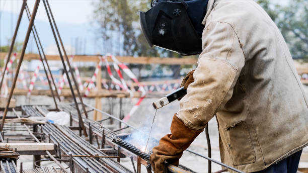 istock Welder at construction site is welding pipe with electrode in helmet. 1184545825