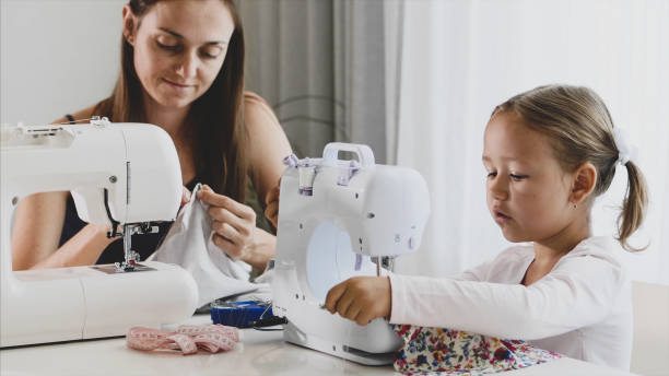 istock Mother and daughter is sewing on a machine together. 1184545884