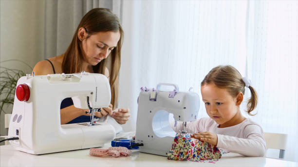 istock Mother and daughter is sewing on a machine together. 1184545896