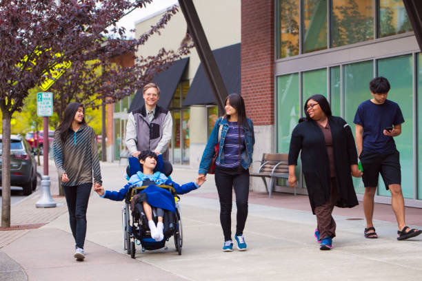 Disabled boy in wheelchair in city  with family and caregiver stock photo