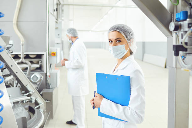 istock A woman in a white uniform with a folder in her hand controls the production process. 1184555398