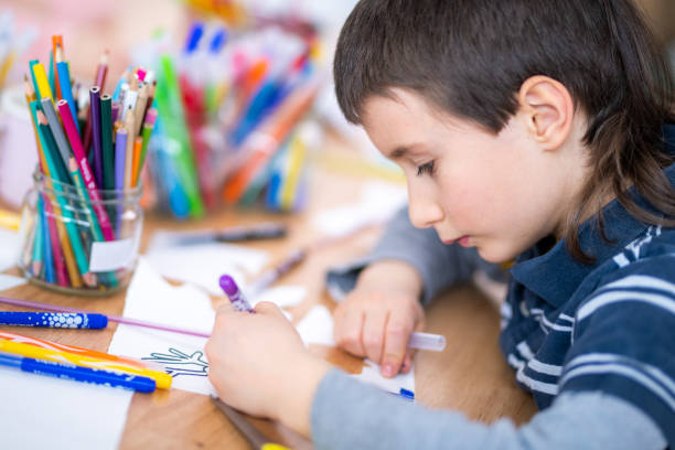 istock Schoolboy drawing on a paper 1184563417