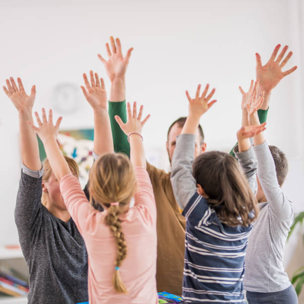 istock Schoolchildren and teachers with arms raised 1184563422