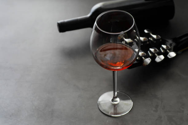 istock Guitar and high glass with red wine on a stone background. 1184563582