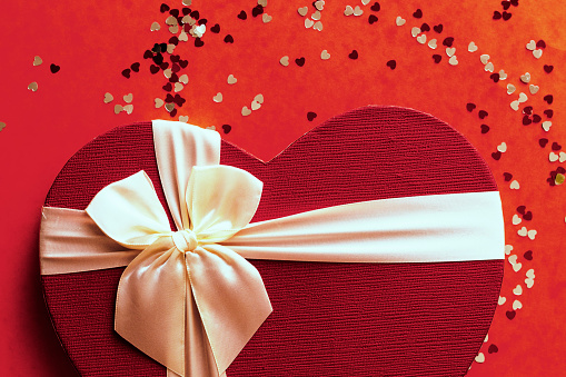 Gift box with red ribbon and empty gift tag on pink background