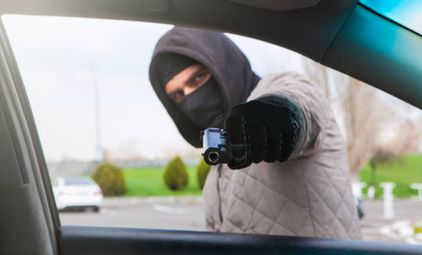 istock criminal robbing a car driver; social issue 1184571150