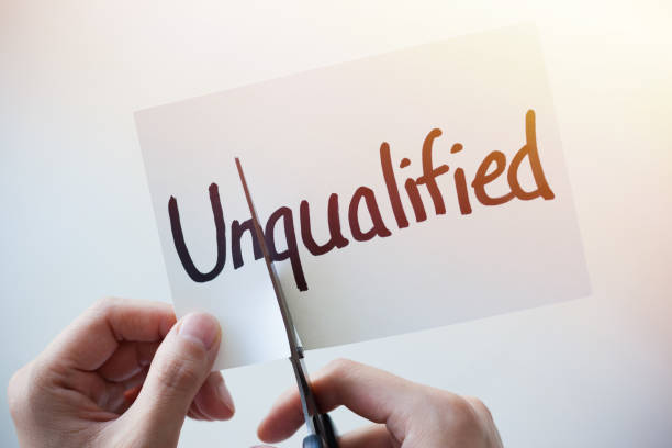 istock Cutting Out the Word Unqualified and Qualified on Paper with Scissors 1184573010