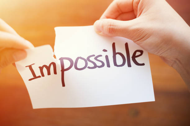 istock Hands Ripping Apart the Word Impossible and Possible Written on Paper 1184573033