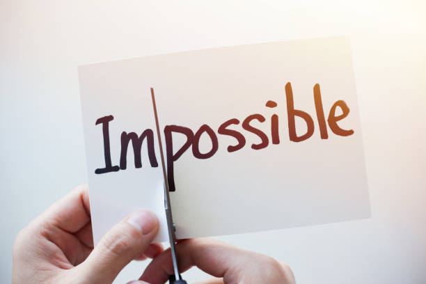 istock Cutting Out the Word Impossible and Possible on Paper with Scissors 1184573050