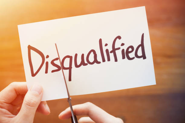 istock Cutting Out the Word Disqualified and Qualified on Paper with Scissors 1184573282