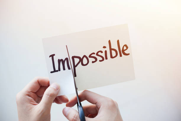 istock Cutting Out the Word Impossible and Possible on Paper with Scissors 1184573359