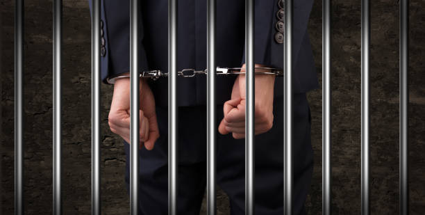 istock Close handcuffed man in jail 1184573880