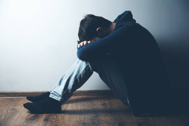 istock sad man sitting on ground on dark background 1184577870