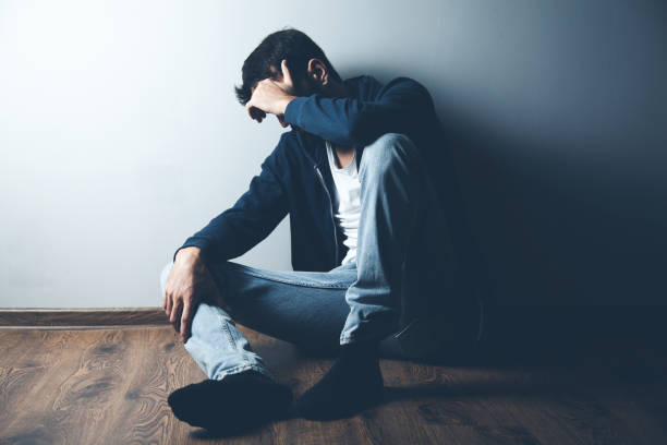 istock sad man sitting on ground on dark background 1184577875