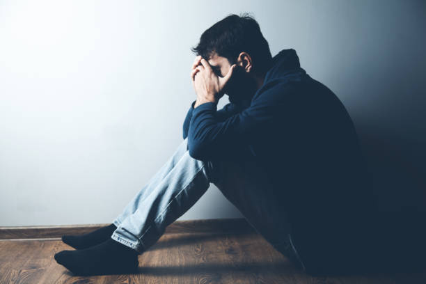 istock sad man sitting on ground on dark background 1184577882