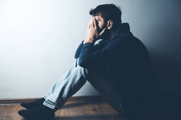 istock sad man sitting on ground on dark background 1184577883