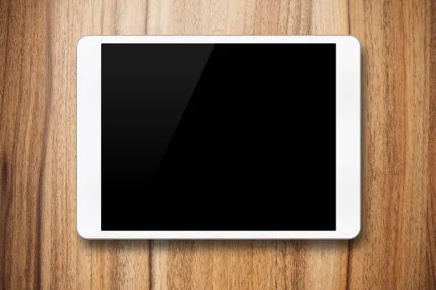 Photo of (Clipping path) Blank white digital tablet on wood background