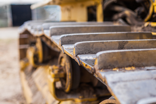 Close-up of crawler bulldozer truck. Earthmoving heavy machinery. Yellow crawler machinery. Yellow Tractor on caterpillar tracks, tractor tracks