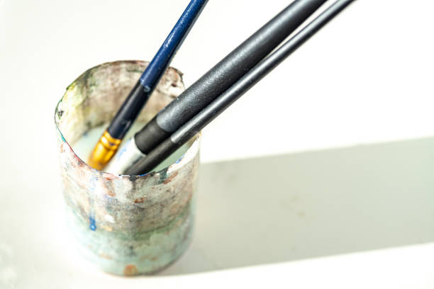 Artist's brush collection displayed in a wooden holder on a colorful table in a creative workspace